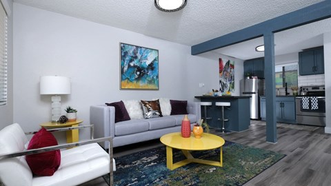 Fusion Las Vegas apartments 89119 open concept living area with modern blue and green, yellow coffee and side table, and view to kitchen.
